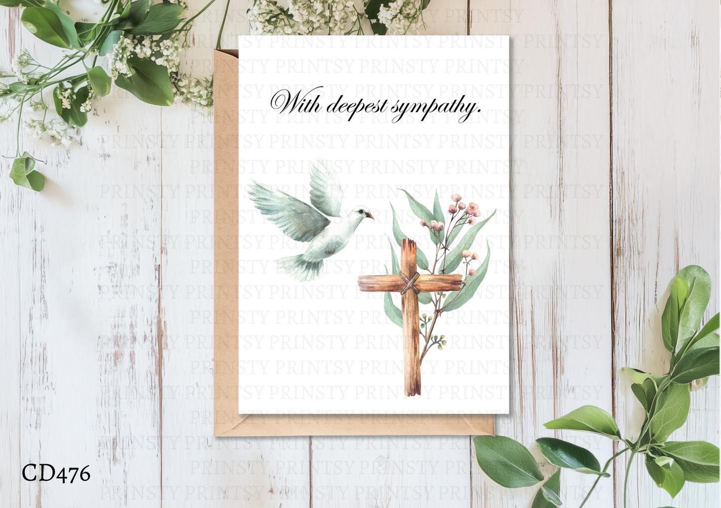 Greeting card with cross and foliage design on a wooden surface with greenery.