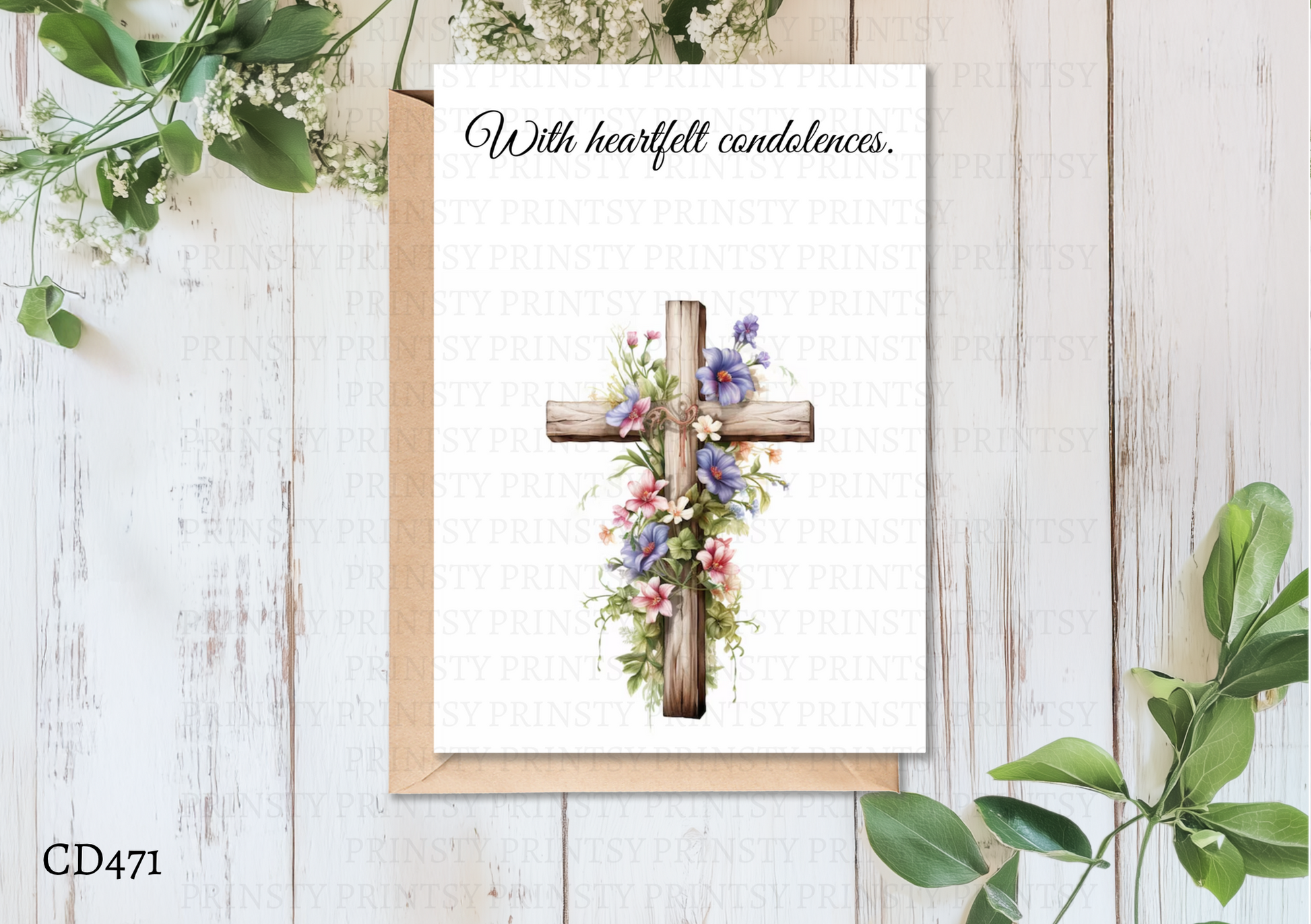 Greeting card with floral cross design on a wooden surface with greenery.