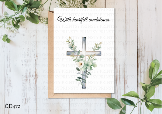 Greeting card with cross and floral design on a wooden surface with greenery.