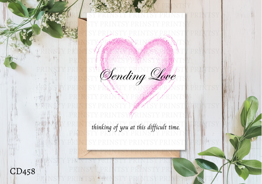 Greeting card with pink heart and text on a wooden surface with greenery
